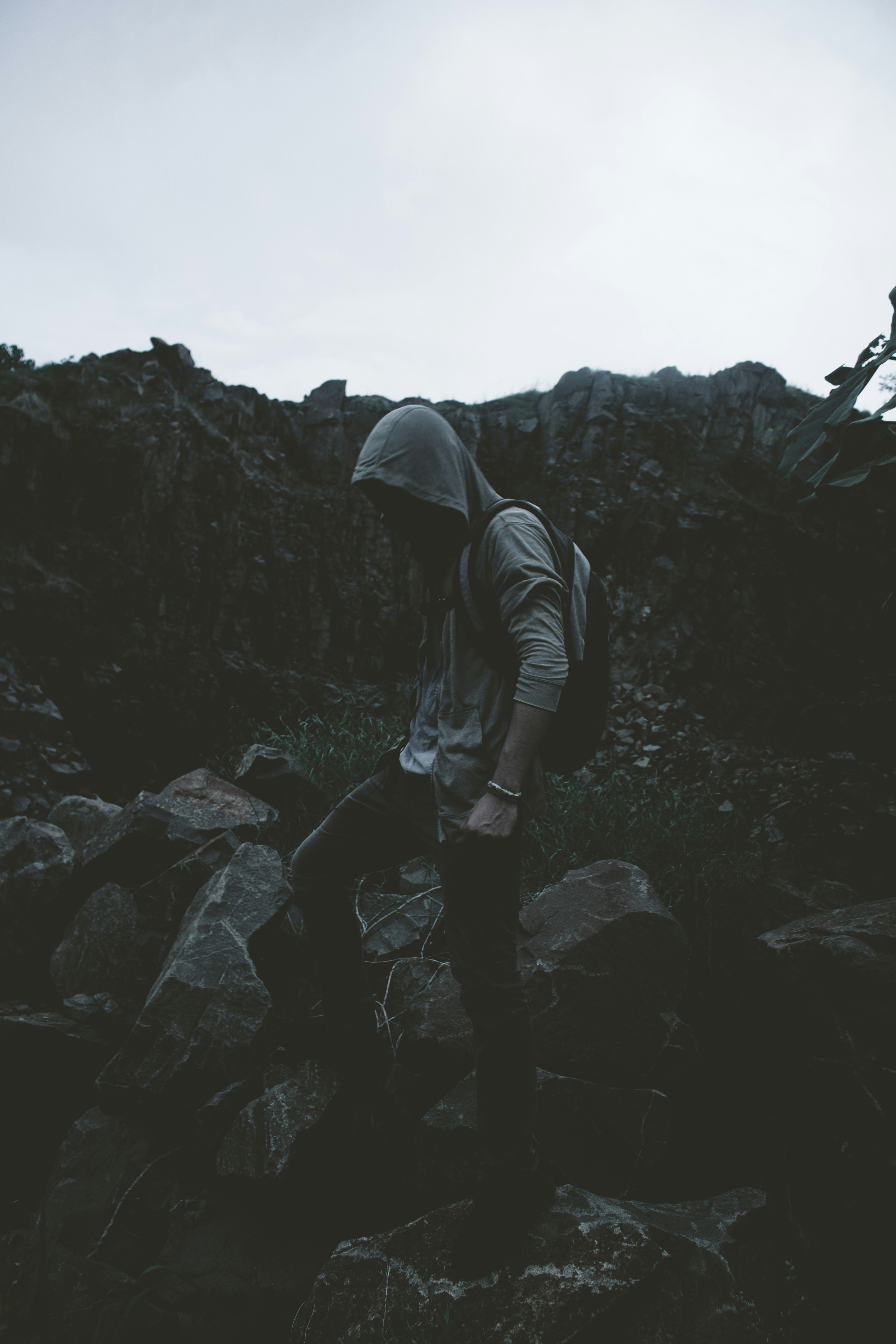 man in hoodie stepping on rocks